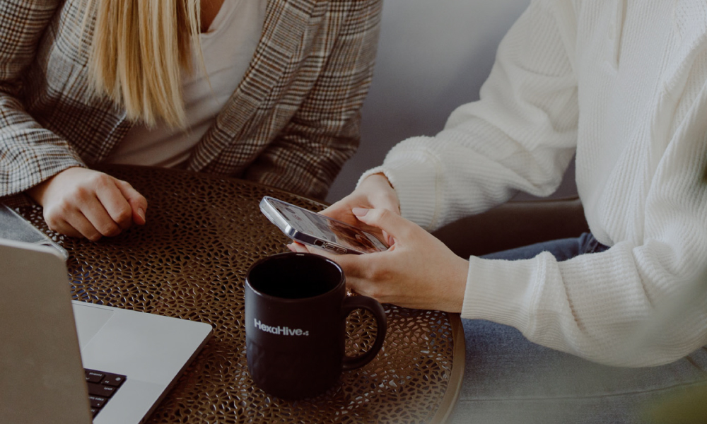 Two employees at HexaHive reviewing engaging content on a cell phone