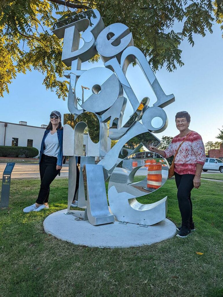 Andrea and her mom standing next to a mirrored sculpture